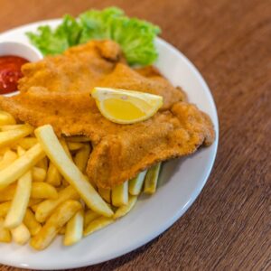 Delicious schnitzel served with crispy french fries, ketchup, and fresh lettuce on a plate.