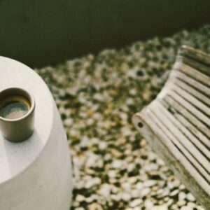 Artistic shot of a coffee cup on a minimalist concrete table with ambient lighting.