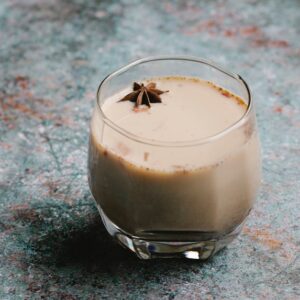 Aromatic chai latte in a glass with star anise garnish on rustic surface.