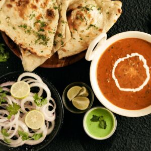 An appetizing Indian meal featuring naan, creamy curry, and fresh condiments.
